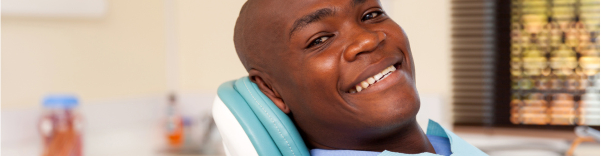 A man sitting in a dental chair, smiling.